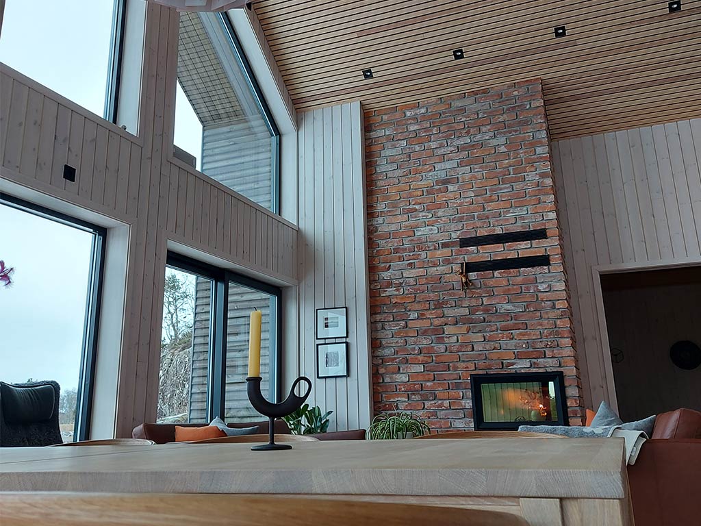 Bilde av stuen til finalist nummer 4 i interiørprisen 2021. Hvitlasert panel på vegger og eikespiler i taket. 