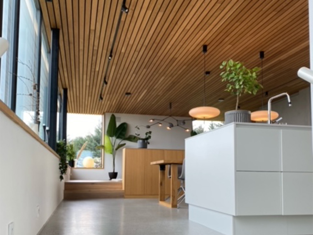 Bilde av kjøkken med spiletak og betonggulv. Nivåforskjell fra kjøkken til stueområdet. Finalist nummer 3 i interiørprisen 2021.