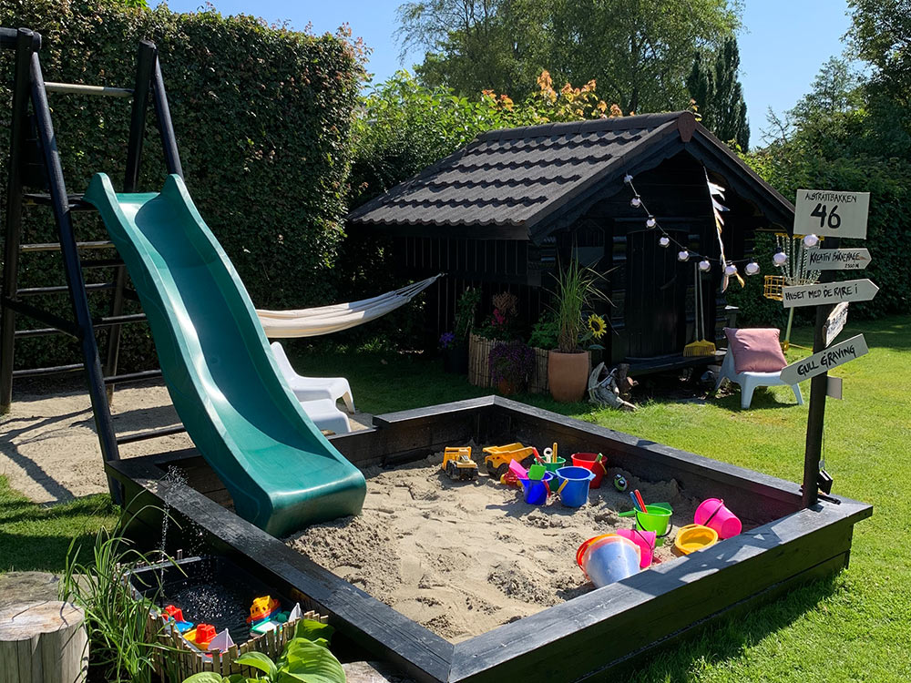 Bilde av lekeplass med sandkasse, huskestativ og lekestue