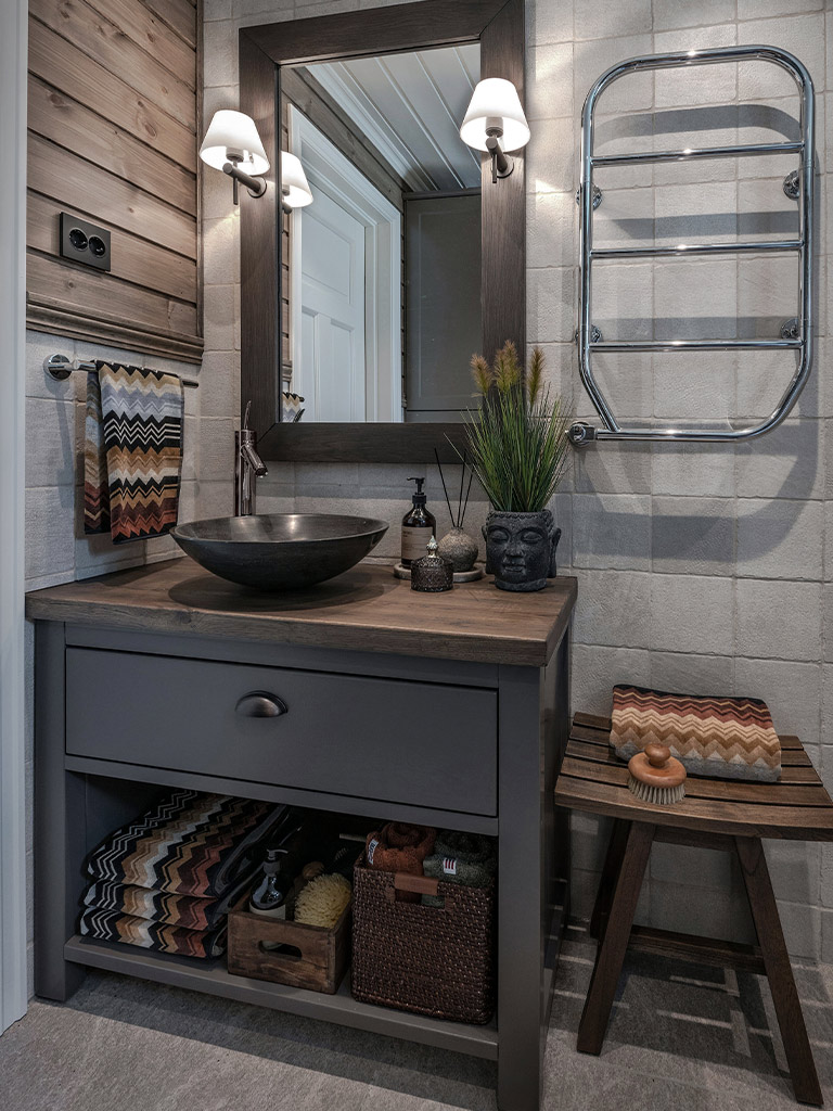 Bilde av modernisert hyttebad med hjemmelaget servantbenk, speil og panel på veggen med mørk beis