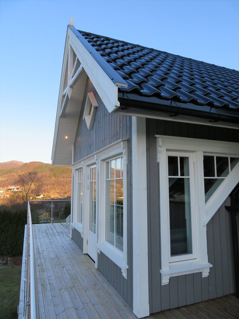 Bilde av hus med verand, mønepynt og detaljering rundt vinduene